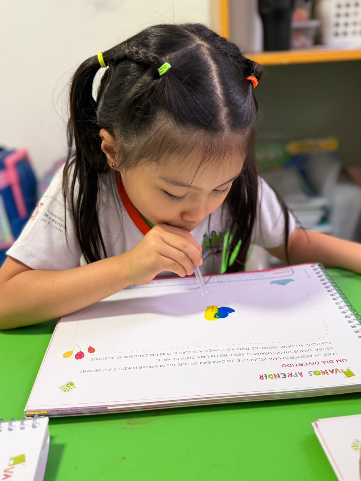 Criança do Jardim escrevendo em caderno na Escola Abra